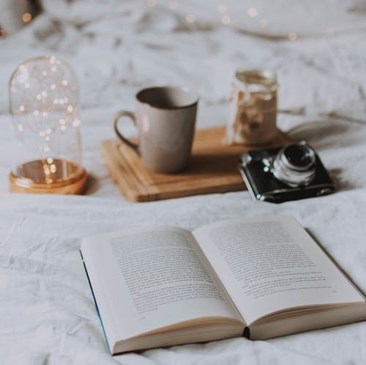 geopend boek op bed met camera vierkant